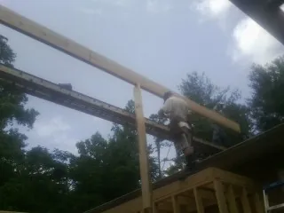 Carpenter setting a ridge beam over a new addition frame — Ice Dam Removal by Roofing Brothers in Bernard