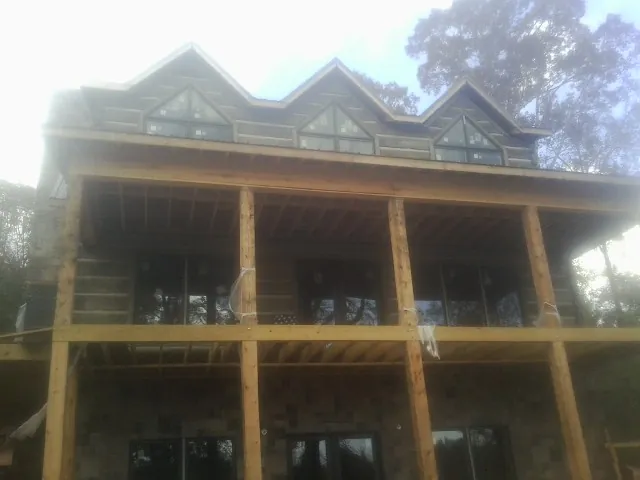 Dormers and porch framing on a large log home under construction — Roof Coating work by our crew in Bernard