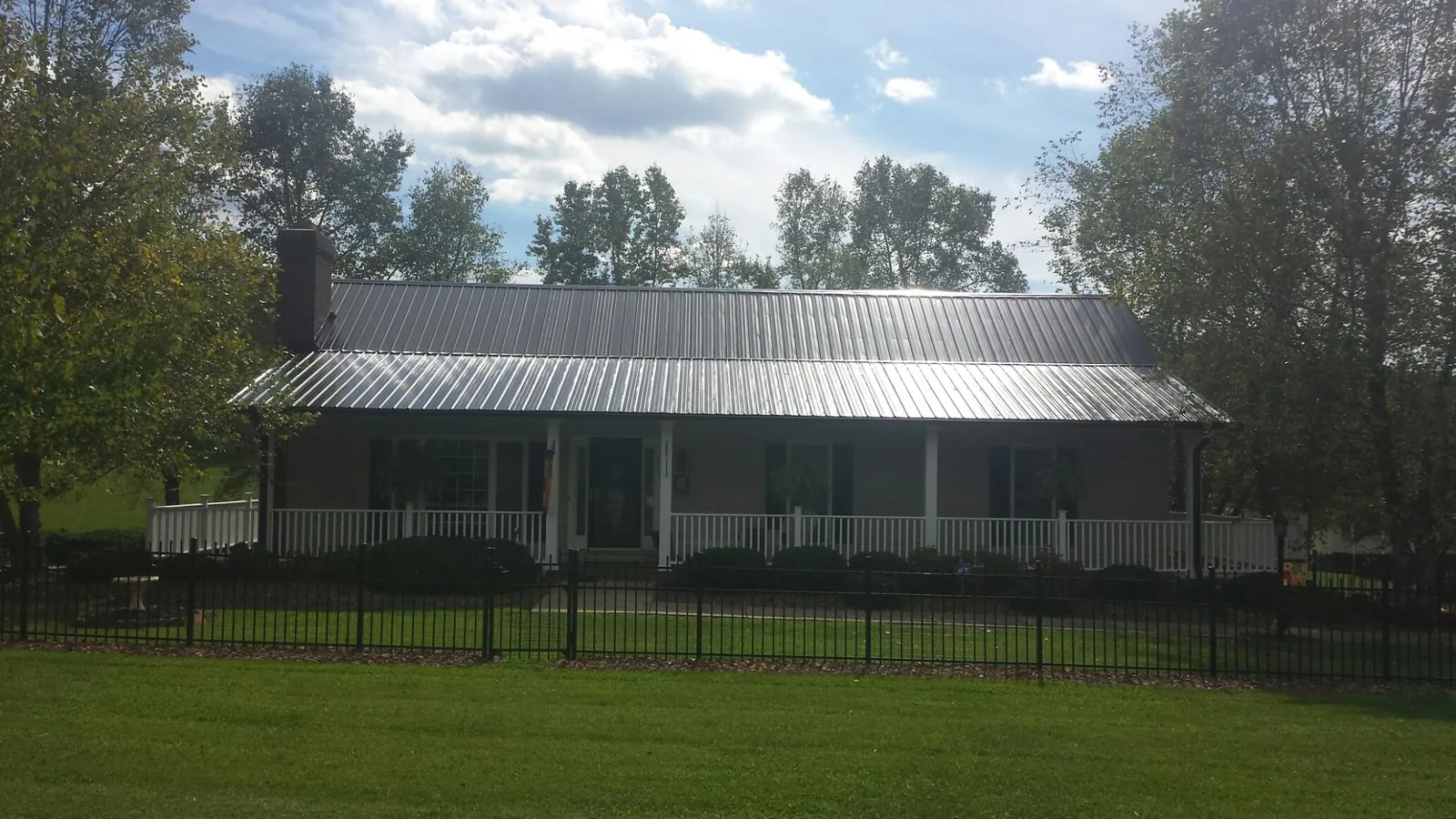 Gray metal roof on a brick ranch with a full width front porch — Gutter Guard Installation work by our crew in Bernard