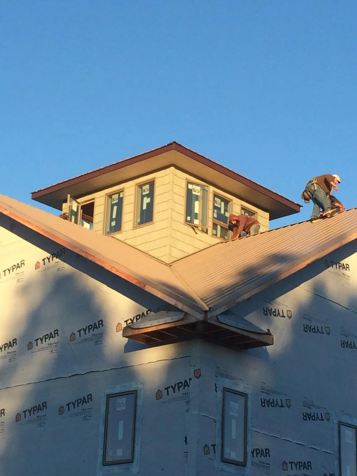 Roofers working around a rooftop cupola on a new metal roof at sunset — Roof Waterproofing in Bernard by Roofing Brothers